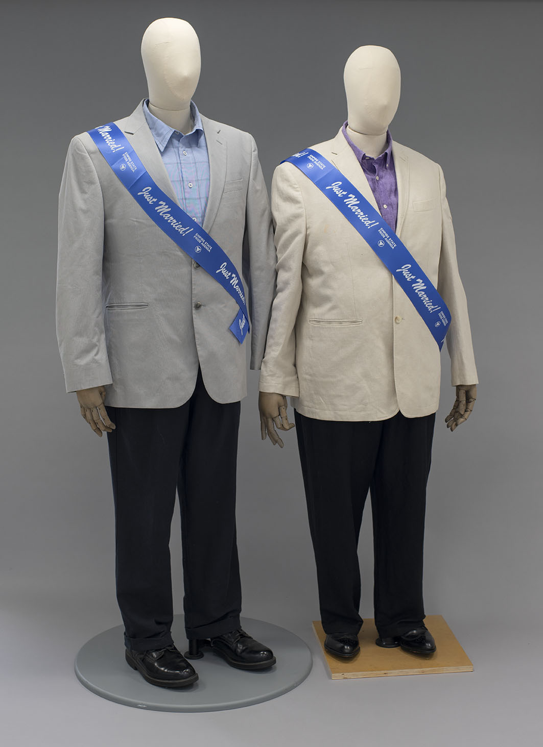 two mannequins wearing men's suits and blue sashes that read "Just Married!"