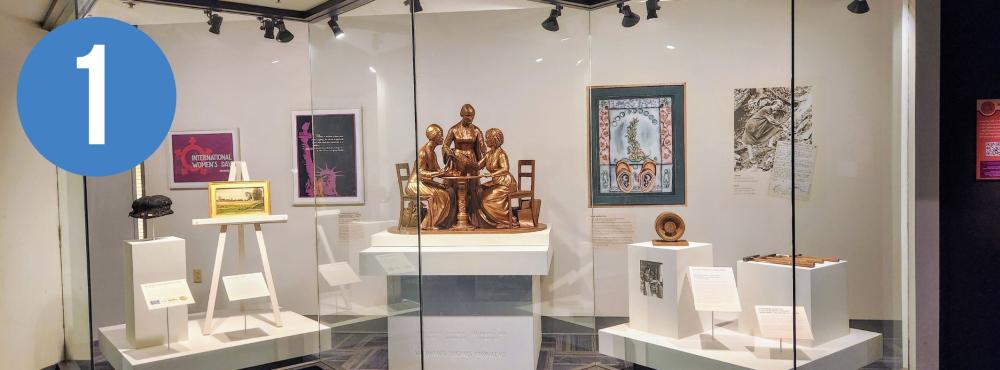 Gallery View of Suffrage Artifacts including posters, buttons, and a model of a statue