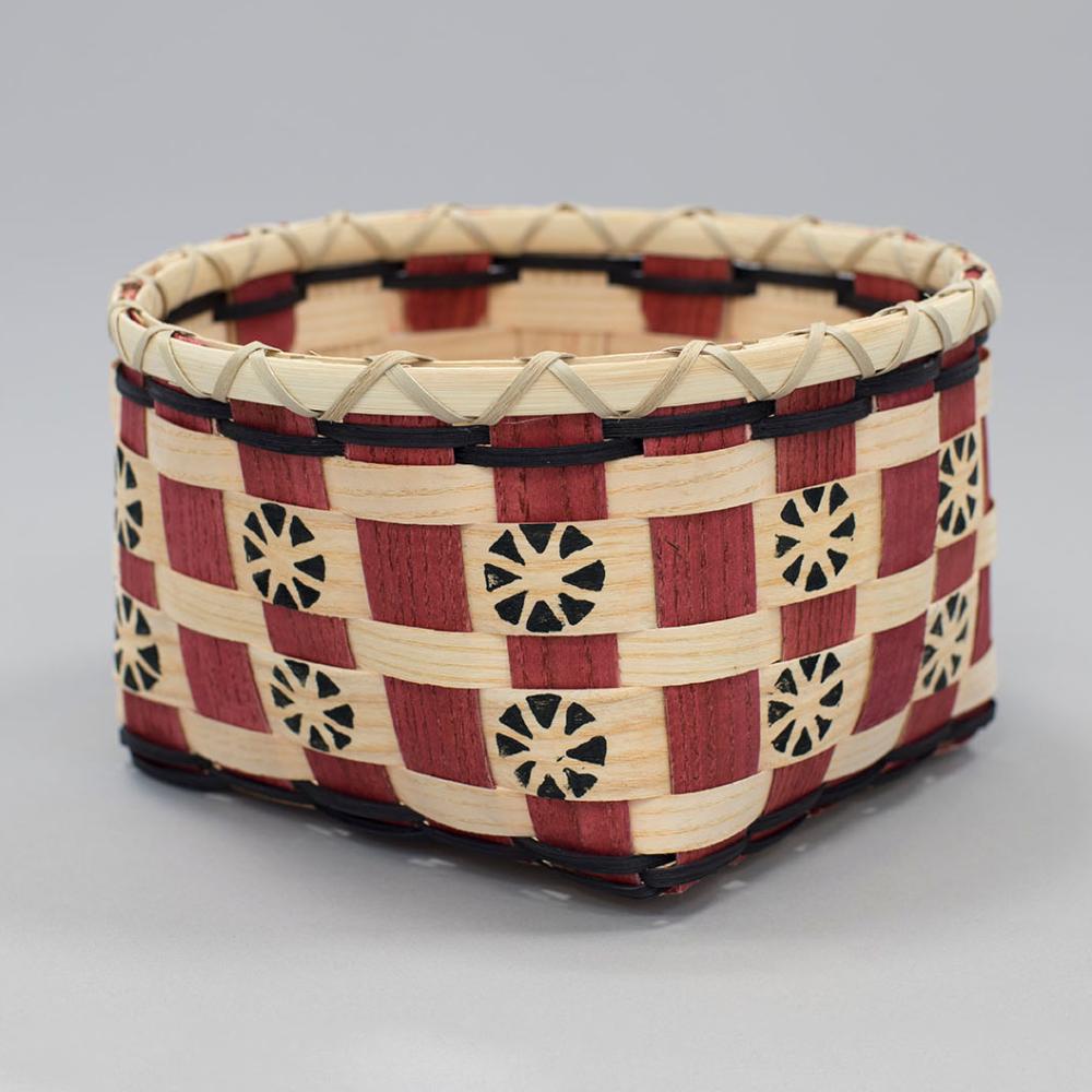Red, white, black woven basket with circular accents throughout and a white/black band at the top