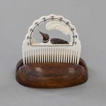 Decorative carved comb with a loon in a wooden base