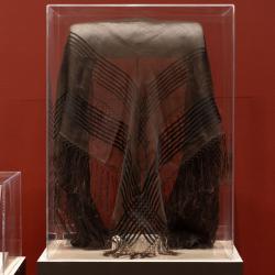 Brown shawl draped in half in a glass exhibit case
