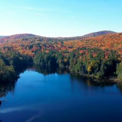 fall landscape of rolling hills with autumnal colors and a body of water in the foreground