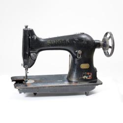 A tabletop machine the size of a microwave with a handwheel on right side. When turned it moves the needle up and down.