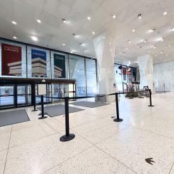 Photo of the NYSM lobby showing white tiled floors, two large white columns, facing the glass walls along Madison Avenue with banners advertising the Libary, Museum and Archives