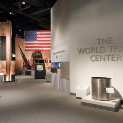 View of gallery entrance to the World Trade Center exhibit. Visible are a steel beam, American flag, and other recovered objects from the World Trade Center site. 