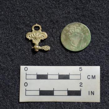 A Georgian period watch winder made of brass (left), and a 1766 British half-penny (right). 