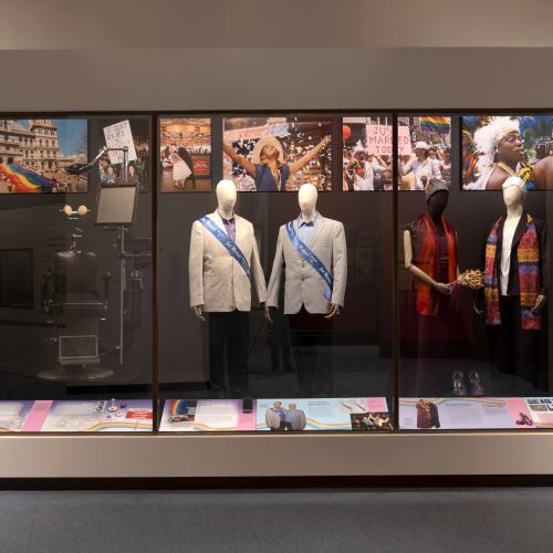 gallery view of Marriage Equality artifacts including two suits and worn by men, and two outfits worn by women