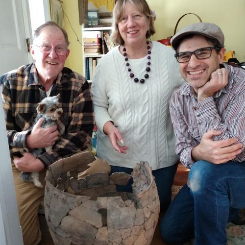 Andrea Lain, archaeology collections manager, and archaeology technician Ralph Rataul pose with Jim Veith Jr. and his dog Scooter, along with the Suffern Rockshelter pot.
