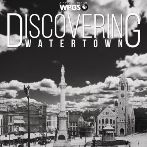 Title text over black/white photo of a downtown area with buildings, a church, and a monument