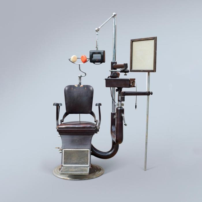 Vintage ophthalmology chair with a pedestal, headrest, and opthalmic accessories